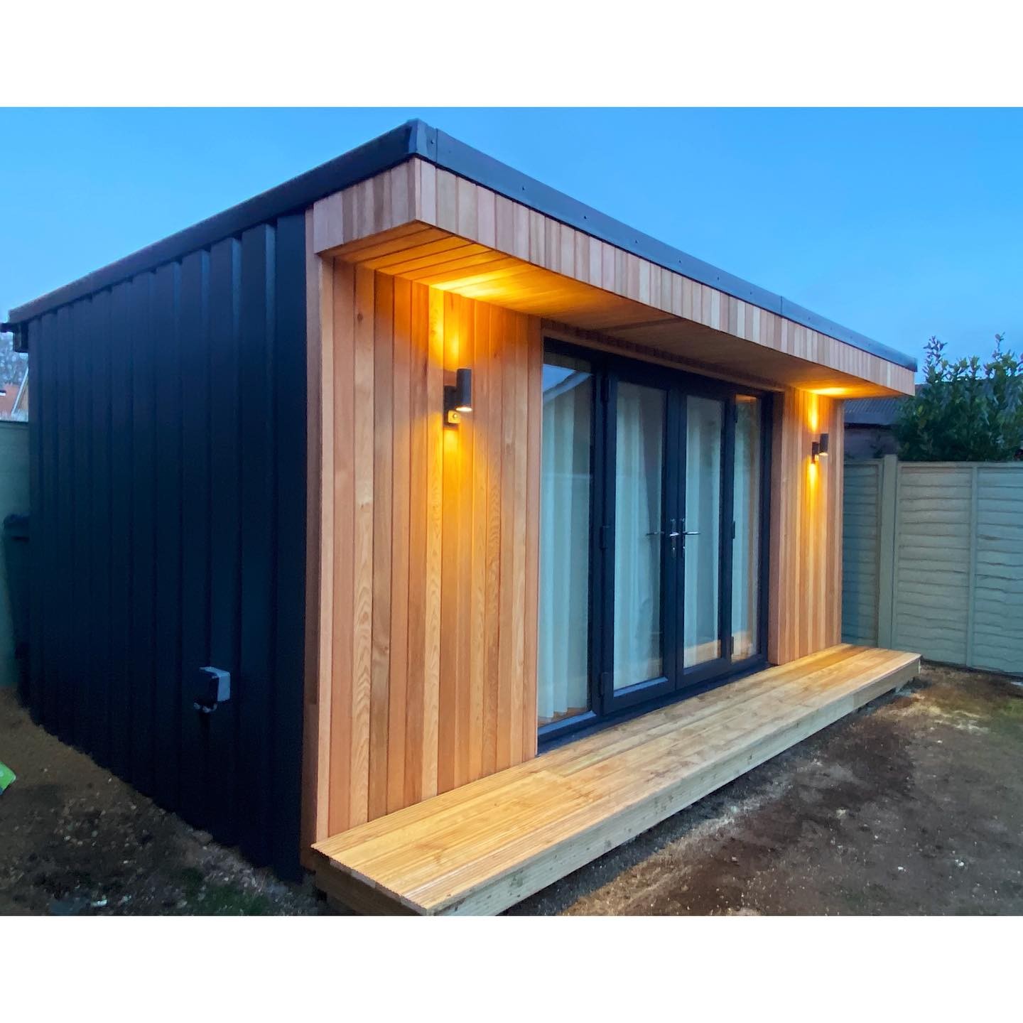 Timber garden room with exterior lighting at dusk